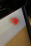 A glowing Hellcat logo projected from the under-door light of a Dodge SRT, highlighting the car’s aggressive branding in a dimly lit garage.