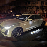 Vehicle side mirror projection showing the Cadillac logo on the pavement.